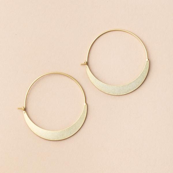 Introducing the Crescent Hoop Gold earrings by Scout Jewelry—elegant gold hoop earrings featuring wide, crescent-shaped accents at the bottom. These nickel-free and hypoallergenic earrings are showcased on a light beige background.