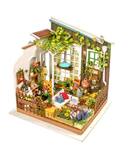 Discover the enchanting Millers Garden DIY Miniature Kit by Hands Craft, featuring a meticulously detailed diorama of a cozy, plant-filled garden room with large windows. This charming dollhouse garden is decorated with various potted plants, vibrant flowers, essential gardening tools, and a quaint seating area complete with a blue chair. A hanging pendant light adds an extra touch of allure to this miniature retreat.