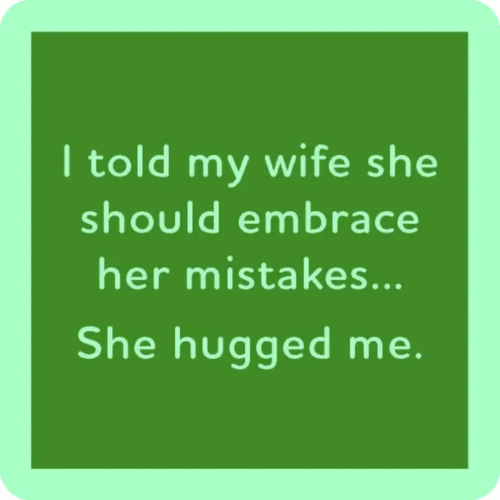 The "she hugged me" coaster by Drinks On Me features a green square design with a humorous message in white text: "I told my wife she should embrace her mistakes... She hugged me." The resin finish and cork backing add charm to this witty piece.