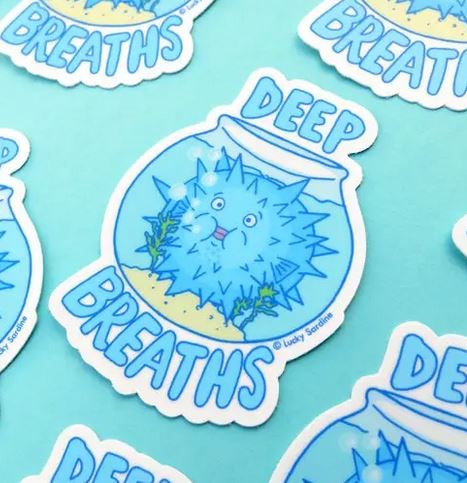 The Deep Breaths Fish Bowl Sticker by Lucky Sardine features a delightful blue pufferfish inside a fishbowl with sand and seaweed. The bowl is labeled "DEEP BREATHS" in bold, blue letters above and below the fishbowl, all set against a calming light blue background. These durable vinyl stickers are both water-resistant and weatherproof.