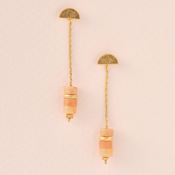 Scout Jewelry's Meteor Thread Sunstone Gold features 14K gold-dipped semi-circular studs, dangling chains, square peach beads, and round gold-toned accents. Displayed on a light beige background, they embody minimalistic charm.