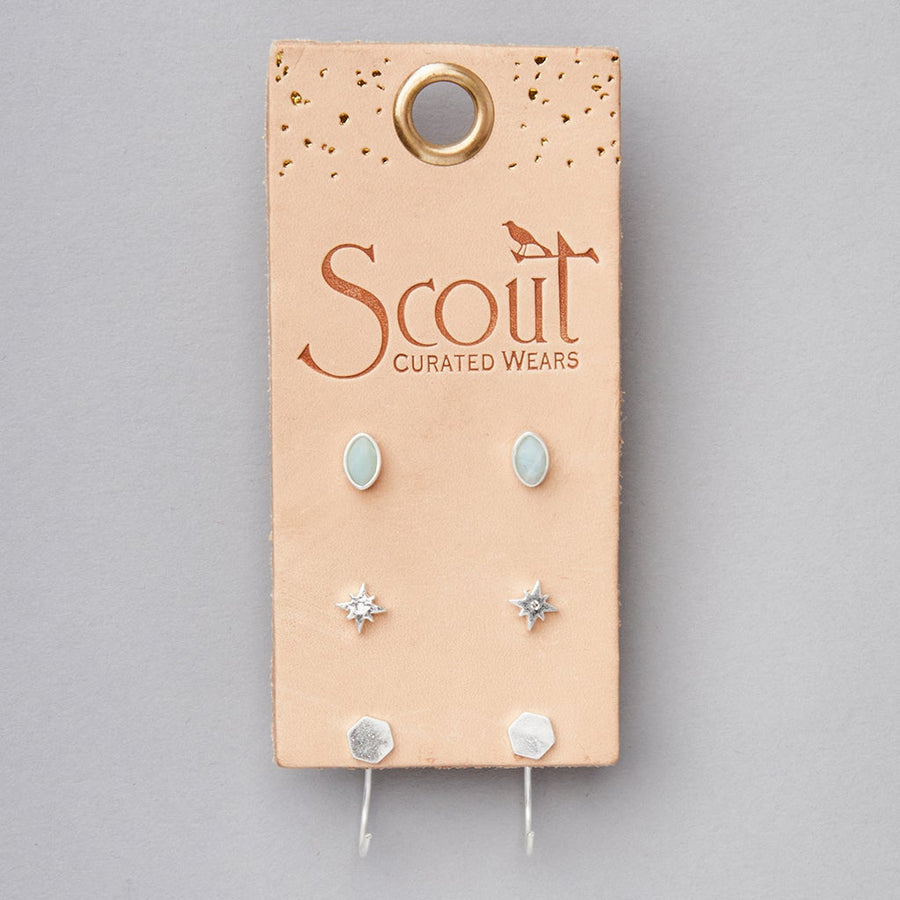 Featuring the hypoallergenic collection from Scout Jewelry, the Gabby Stud Trio Silver includes semi-precious stone light blue ovals, star-shaped silver studs, and hexagonal silver stud earrings, all on a tan leather tag.