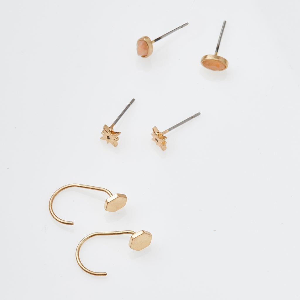 The Gabby Stud Trio Gold, crafted by Scout Jewelry, includes two pairs of hypoallergenic gold-toned stud earrings with intricate flower and oval designs, as well as a pair of hook earrings featuring geometric faceted shapes. All pieces are thoughtfully displayed on a white background to highlight their elegance and ensure maximum comfort.