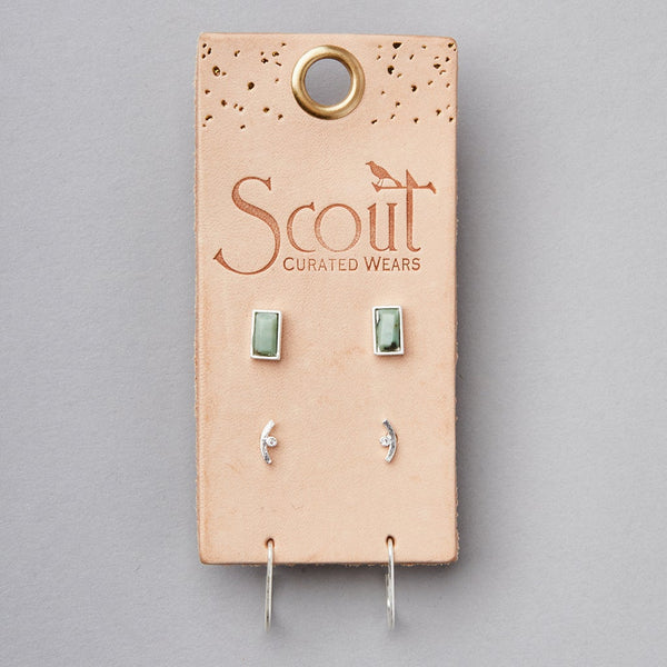 A pair of small green rectangular semi-precious stone studs and a pair of curved silver hypoallergenic earrings with tiny stones, part of the Courtney Stud Trio Silver collection by Scout Jewelry, are displayed on a tan leather card with a gold ring hole at the top. The card is stamped with "Scout Curated Wears" and features a bird graphic.