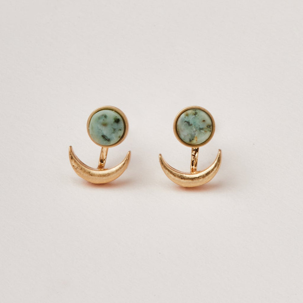 The Moon Phase African Turq/Gold earrings by Scout Jewelry showcase circular gemstones with a delicate light blue-green pattern as studs, each paired with an adjustable brass crescent moon design hanging below. Displayed against a plain white background, these hypoallergenic earrings are both stylish and comfortable for sensitive ears.