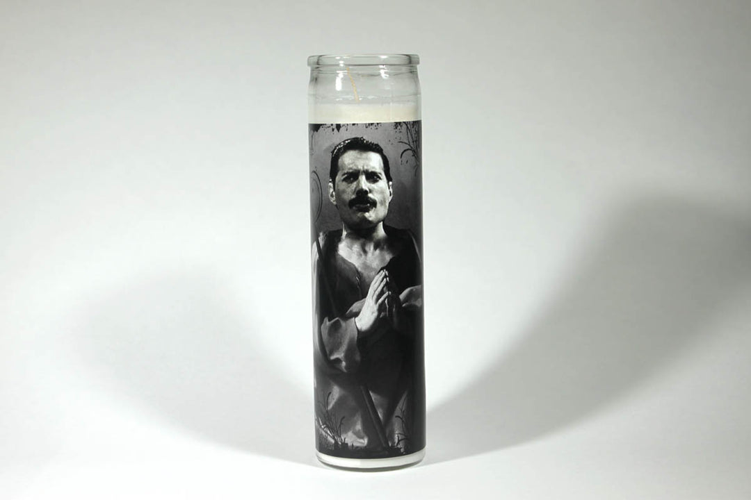 The BOBBYK BOUTIQUE Freddie Mercury Candle features a black-and-white illustration of the iconic rock star with hands clasped in prayer, set against a plain white background. This unique piece is perfect for any celebrity shrine.