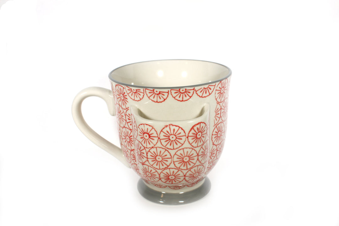 The Stoneware Mug with Tea Bag Holder by CreativeCoOp showcases a light interior adorned with red circular designs, complemented by a gray rim and base. It includes a convenient front pocket and is both dishwasher and microwave safe, all styled against a white background for a timeless appearance.