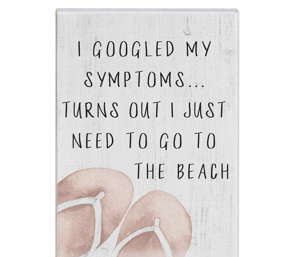 The Googled Symptoms Beach sign by SincereSurroundings features a charming light grey wooden background with the text "I GOOGLED MY SYMPTOMS... TURNS OUT I JUST NEED TO GO TO THE BEACH" displayed in black uppercase letters. This handcrafted piece includes an illustration of brown flip-flops at the bottom left, making it perfect for any shelf display.