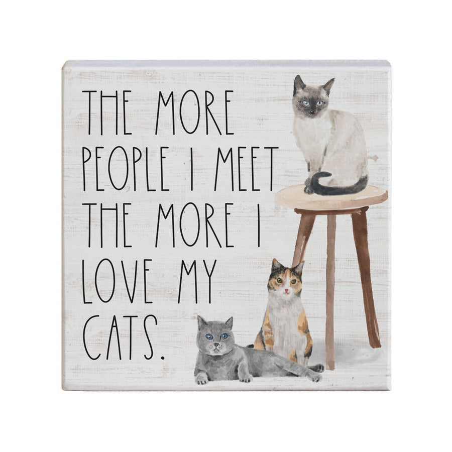 The "Love My Cats" handcrafted decorative sign from SincereSurroundings displays the phrase, "THE MORE PEOPLE I MEET THE MORE I LOVE MY CATS." The design features three cats: a Siamese cat sitting on a wooden stool, a gray cat lying down, and a calico cat sitting upright. It's perfect for easy display.