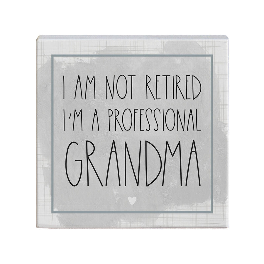 The "Not Retired" sign by SincereSurroundings features a handcrafted design with a gray and white background, displaying the phrase "I am not retired, I'm a professional grandma" accented by a small heart beneath the text. It's perfect for adding charm to your shelf display and is carefully made in Rock Rapids, IA.