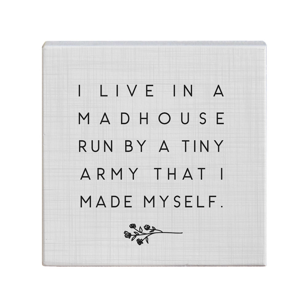 The handcrafted decorative canvas, "Tiny Army," from SincereSurroundings features the phrase, "I live in a madhouse run by a tiny army that I made myself," accompanied by a delicate floral design. It's an ideal addition to your shelf display, bringing character and charm to your space.