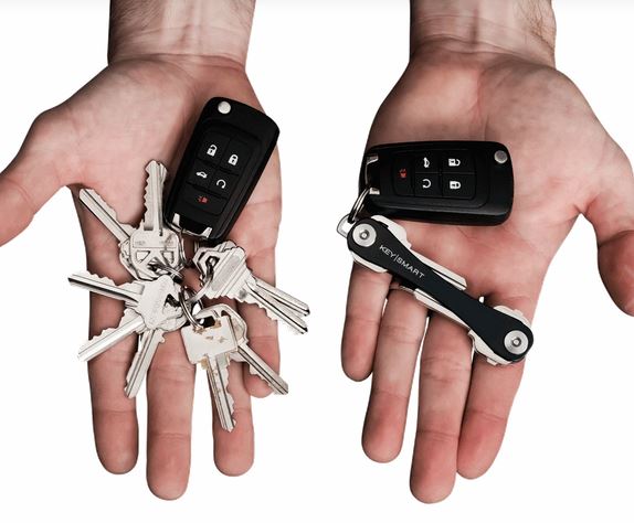 Two hands hold different sets of keys and car remotes. The left hand holds several loose keys with a car remote, while the right efficiently manages a KeySmart Key Holder and another car remote, maximizing pocket space.