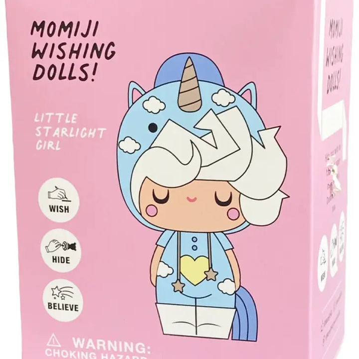 A pink box featuring a cartoon image of the "Little Starlight Girl" Momiji Wishing Doll. The vinyl doll has white curly hair and dons a blue unicorn costume complete with a hood, stars, and a heart on the chest. Accompanying symbols for "Wish, Hide, Believe," are presented alongside the iconic Momiji guardian design and a choking hazard warning.