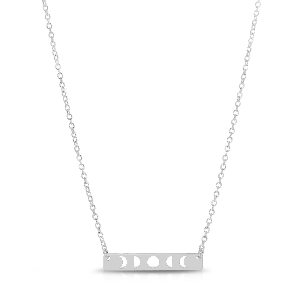 The Moon Phase Necklace Silver by LuckyFeather is a delicate sterling silver accessory featuring a horizontal bar pendant with intricate cutouts of the moon's phases, including crescent, half, and full moon shapes. Ideal for astrology enthusiasts, the pendant hangs gracefully on a simple silver chain.