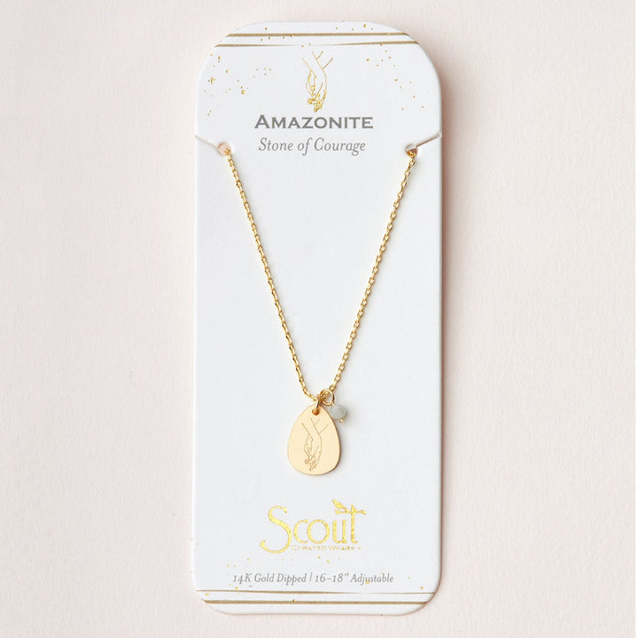 The Scout Jewelry Intention Neck Amazonite/Gold necklace showcases an oval pendant with semi-precious gemstones. It's on a card reading "Amazonite Stone of Courage" and features a 14k gold-dipped, adjustable chain (16-18 inches).