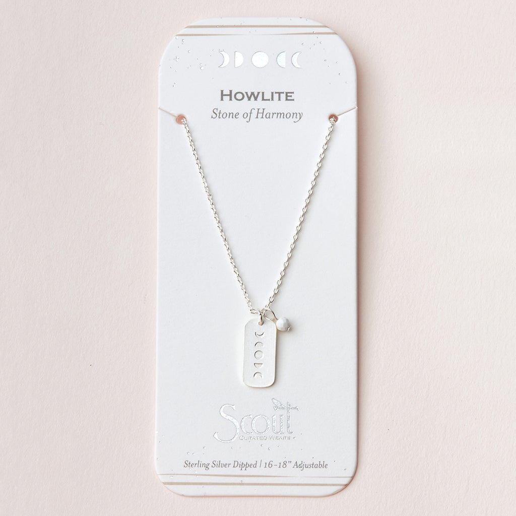 The Intention Neck Howlite/Silver necklace by Scout Jewelry features a silver rectangular pendant with moon phase symbols. It comes attached to a white card that reads "Howlite, Stone of Harmony." The engraved charm indicates that the necklace is sterling silver dipped and adjustable between 16-18 inches.