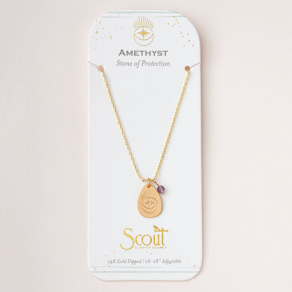 An "Intention Neck Amethyst/Gold" necklace by Scout Jewelry, featuring a pendant with a small amethyst stone, is displayed on a white card. The card reads "AMETHYST - Stone of Protection" and "Scout," along with "14K Gold Dipped 16”-18” Adjustable Brass Chain" at the bottom, finished with decorative gold accents.