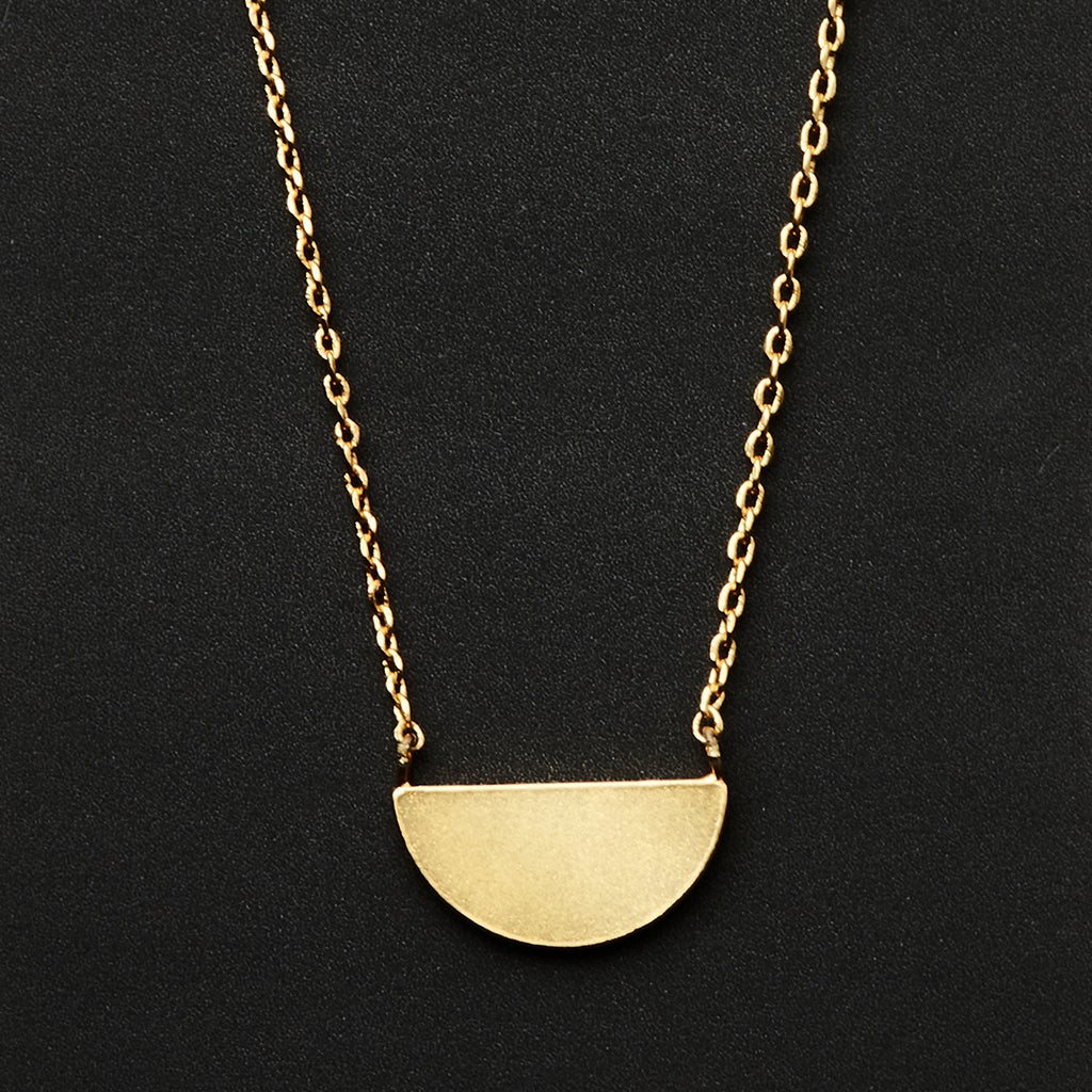 The Refined Neck Half Moon/Gold by Scout Jewelry features an exquisite 18k gold vermeil chain with a half-circle pendant set against a black background. Its adjustable chain guarantees a perfect fit.