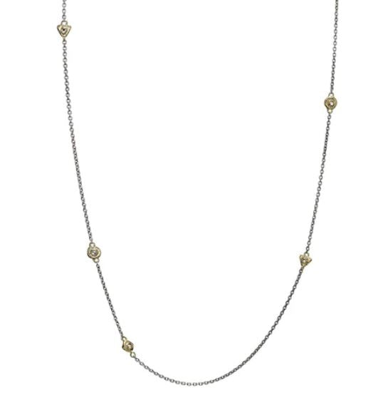 The Points of Light Chain Silver 24in by Waxing Poetic boasts a delicate sterling silver chain adorned with evenly spaced small round gold accents. The subtle contrast between the silver hue and the shimmering crystal accents offers an elegant touch, making it perfect for any occasion.