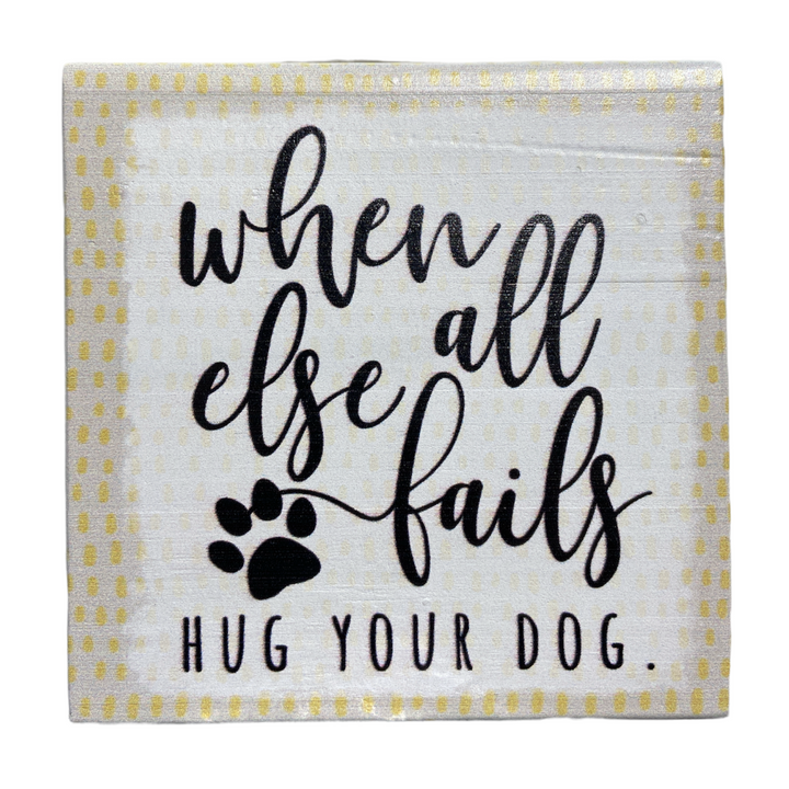 The "Hug Your Dog" decorative sign, handcrafted by SincereSurroundings, features a dotted border and is perfect for your shelf display in Rock Rapids. It includes the text "When all else fails, hug your dog" accompanied by a charming paw print graphic.