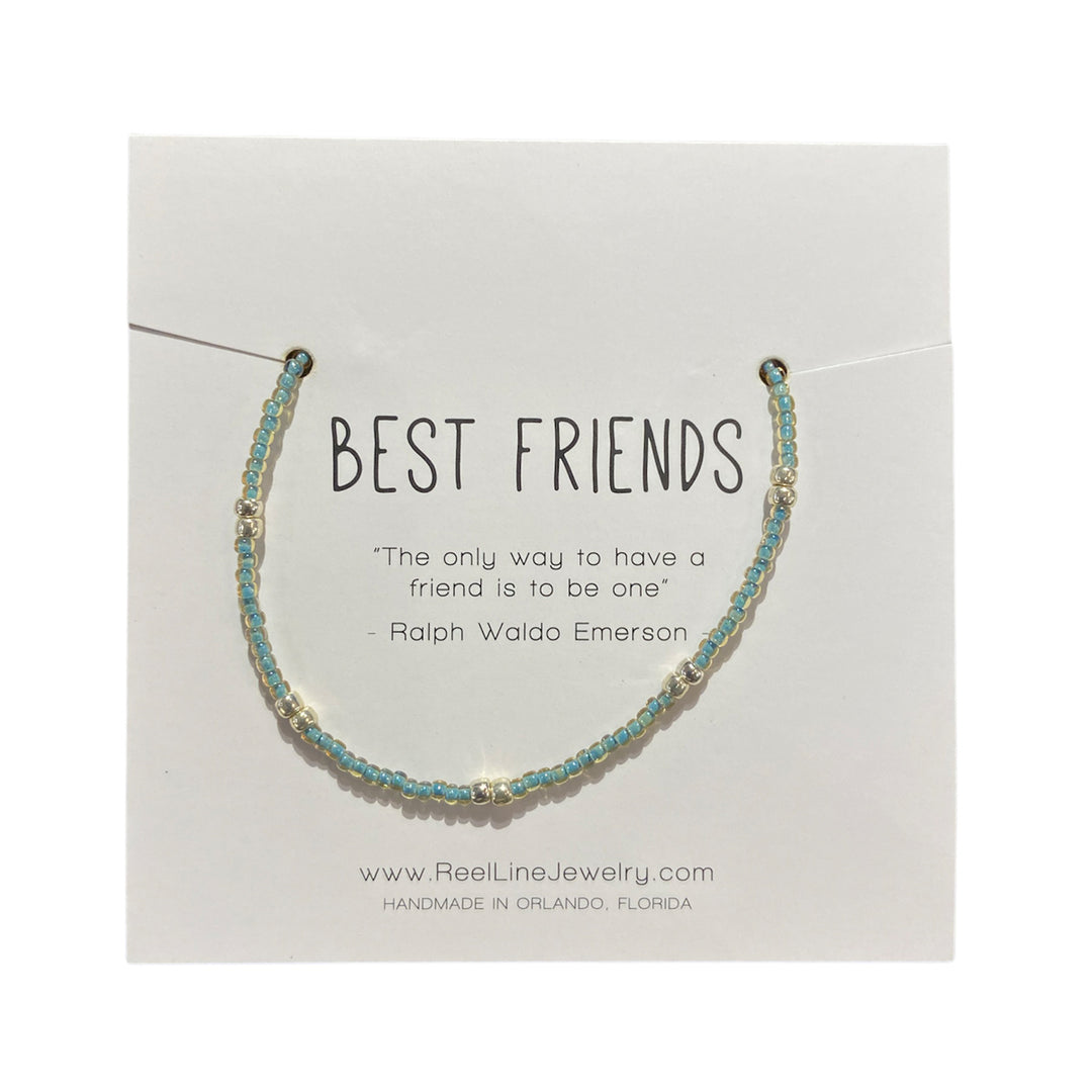 Displayed on a white card, the Best Friends - Eucalyptus and Silver bracelet by Reel Line Jewelry features a delicate, thin design with alternating eucalyptus-colored and silver beads. The card is inscribed with "BEST FRIENDS" at the top, followed by a quote from Ralph Waldo Emerson: "The only way to have a friend is to be one." The adjustable links ensure comfort. This beautiful piece is handcrafted in Florida.