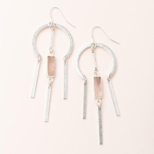 Discover the Dreamcatcher Earring Rose Quartz Silver by Scout Jewelry, showcasing a pair of silver geometric earrings with a central rectangular semi-precious stone. Three hanging metal bars and semicircular hoops seamlessly connect each element, enhanced with 14k gold accents, to create a modern and elegant look against a light background.