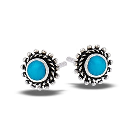 The Welman Turquois Round Bali Style Granulation Silver Stud earrings feature vibrant blue stones at their center, surrounded by a twisted rope design and small metallic beads. This elegant and intricate pair of sterling silver stud earrings complements any outfit and is mask-friendly.