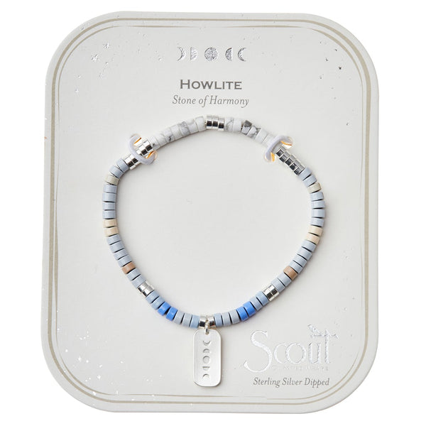 The "Intention Charm Howlite Silver" bracelet, featuring round beads in shades of white, gray, and blue and adorned with a sterling silver dipped charm, is beautifully showcased on a card titled "Stone of Harmony." Crescent moon symbols surround the brand name "Scout Jewelry," adding an element of positive intention.