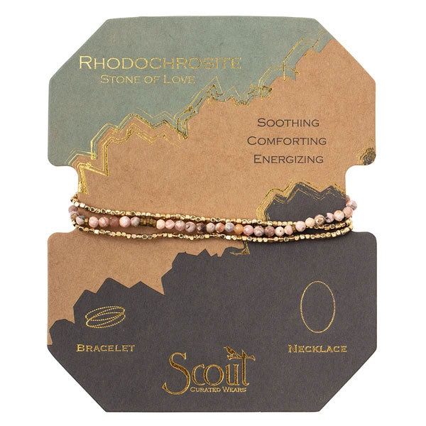 The Rhodochrosite/Gold Delicate Wrap by Scout Jewelry showcases semi-precious pink rhodochrosite gemstone beads on a gold chain, elegantly presented on a cardboard backing. The card highlights "Rhodochrosite: Stone of Love" and its soothing, comforting, energizing qualities. The text reads "bracelet necklace.