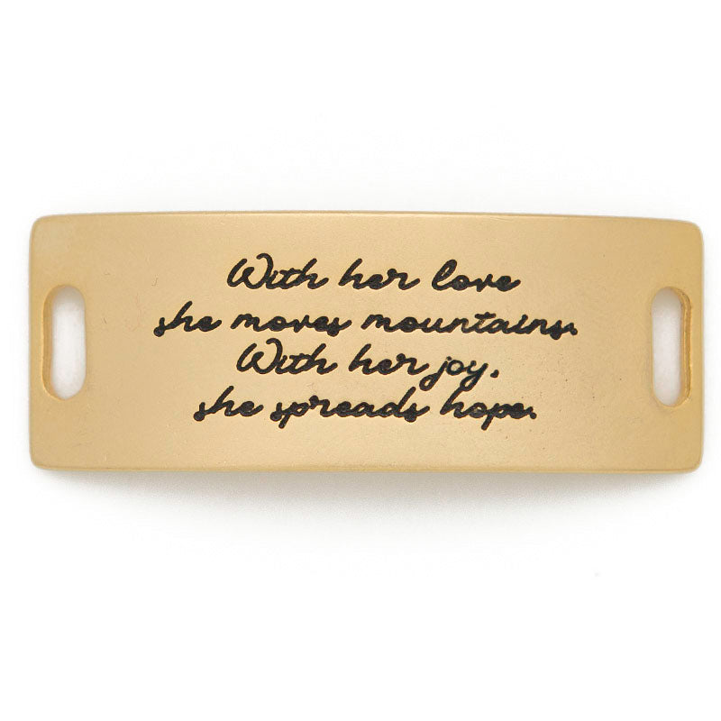 A beige rectangular plaque featuring two slots on each side, adorned with gold cursive text that reads: "With her love, she moves mountains. With her joy, she spreads hope." This elegant piece is from LENNY & EVA, aptly named "With her love she moves mountains.. Gold.