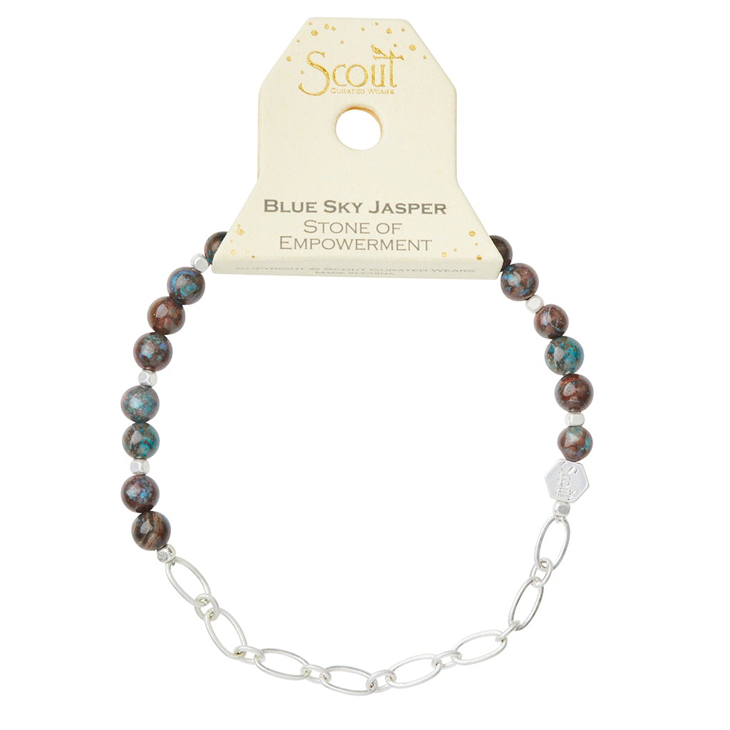 A bracelet named Chain Bracelet Blue Sky Jasper/Silver showcases semi-precious blue sky jasper stone beads elegantly paired with a silver paperclip chain. The packaging features Scout Jewelry and highlights "Blue Sky Jasper, Stone of Empowerment.