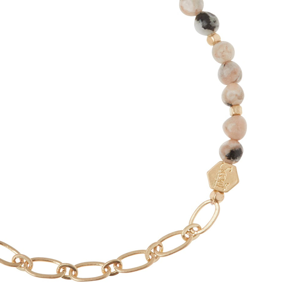 The Chain Bracelet Rhodonite/Gold by Scout Jewelry showcases a paperclip chain blending with round marbled and solid beads in alternating colors. A gold hexagonal bead hangs from a link, while semi-precious gemstones infuse elegance into this modern design.