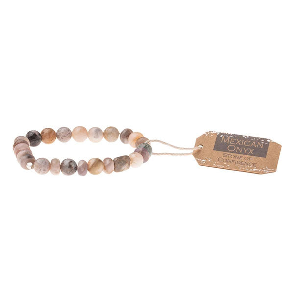 The Mexican Onyx Stone Stacking Bracelet by Scout Jewelry is crafted from polished, multicolored Mexican Onyx semi-precious beads strung on a stretch cord. It features an attached brown tag reading "MEXICAN ONYX - STONE OF CONFIDENCE," connected with a white string.