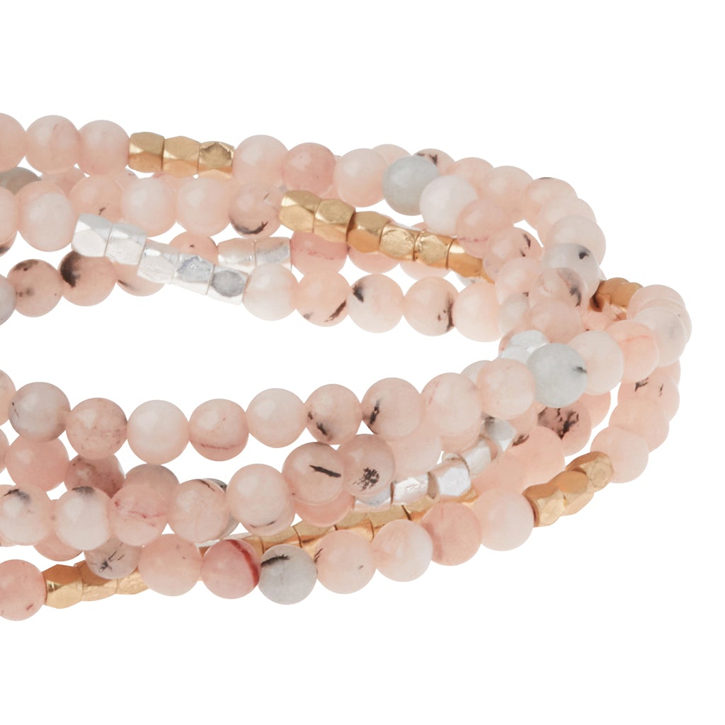 Close-up of the Stone Wrap Morganite/Blk Tourmaline bracelet by Scout Jewelry, showcasing pink gemstones with semi-precious gold and silver accents. The beads are arranged in multiple strands, varying in shade and pattern with soft pinks and subtle white markings.