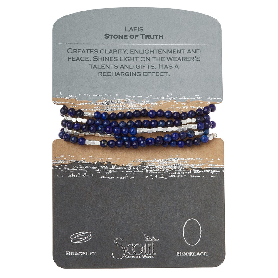 A store display card highlights the "Stone Wrap Lapis Silver," a bracelet or necklace from Scout Jewelry. Crafted with semi-precious gemstones, it features deep blue and white stone beads and describes "Lapis - Stone of Truth," offering promises of clarity, enlightenment, peace, and a recharging effect. The brand name "Scout" is prominently displayed.