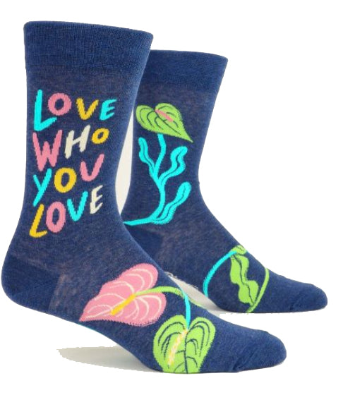 Introducing the Love who you love Socks by Blue Q: a pair of dark blue combed cotton socks adorned with vibrant, colorful designs and text. One sock prominently displays the phrase "LOVE WHO YOU LOVE" in multicolored letters, while both socks feature decorative elements of plants and leaves in bright, contrasting colors. Designed to fit men's shoe sizes 7-12.