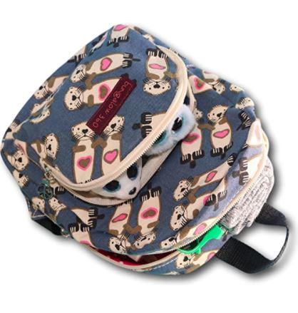 Introducing the Mini Back Pack Sea Otter by Bungalow 360: This vibrant children's backpack is made from naturally durable cotton canvas and showcases an adorable sea otter pattern against a blue background. The charming otters are depicted holding pink hearts. It features an adjustable nylon strap for optimal comfort and a zippered closure that offers a glimpse of the contents when slightly open.