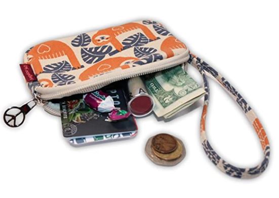 The Tiny Wristlet Sloth by Bungalow 360, made from durable natural cotton canvas and adorned with a charming orange and white sloth pattern, lies open to reveal its contents: a folded banknote, coins, lip balm, and a small plastic card. The wristlet features a zipper closure and comes with an attached peace symbol keychain.