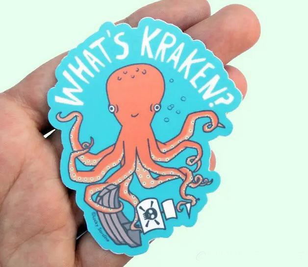 A hand holds a Lucky Sardine What’s Kraken Pirate Ship Octopus Sticker, which features a cartoon orange octopus surrounded by bubbles on a blue background. Above the octopus, the phrase "What's Kraken?" is written in white text. The octopus has a pirate ship and a pirate flag with a skull and crossbones. This weatherproof, dishwasher-safe sticker is perfect for any adventure.