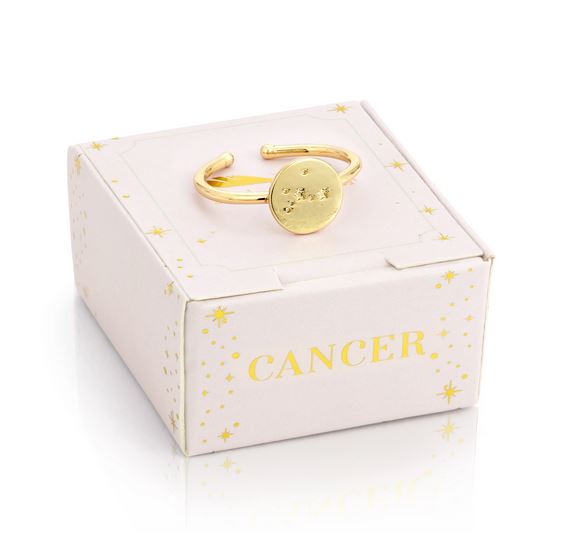 The stylish Cancer Signet Ring by LuckyFeather, featuring a 14k gold-dipped finish, is elegantly displayed on a white box decorated with gold star patterns and the word "CANCER" in vibrant gold. Its circular face highlights the Cancer constellation and includes an adjustable band for an ideal fit.