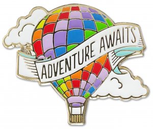 The PeterPauperP Adventure Awaits Balloon Pin features a vibrant hot air balloon illustration with a patchwork of colorful squares. A ribbon draped across the balloon reads "Adventure Awaits," surrounded by white clouds and a light blue sky, creating a whimsical, uplifting design perfect for an enamel pin.