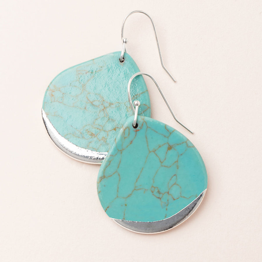 Introducing the "Dipped Teardrop Earring Turq/Silver" by Scout Jewelry: these minimalistic teardrop-shaped earrings showcase turquoise stones adorned with natural, veined patterns and accented in sterling silver. Crafted to be hypoallergenic, they come with silver hooks for easy wearing and are elegantly displayed on a light, neutral background.