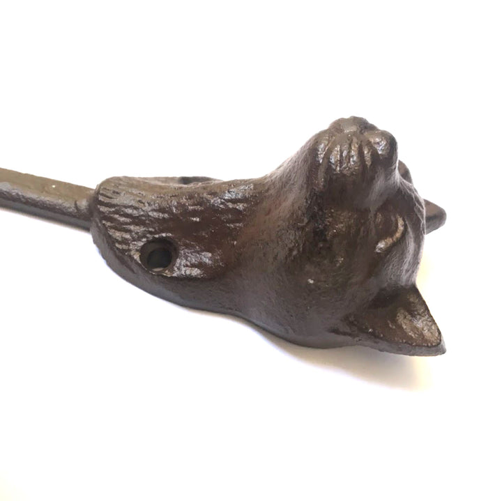 Introducing the UPPER DECK Cat Hook—a dark brown cast iron bottle opener crafted to resemble a cat's head, measuring 6" x 2". This charming tool features a hole in one of the ears for convenient hanging or mounting. The detailed design showcases noticeable fur texture and pointed ears against a contrasting white background.