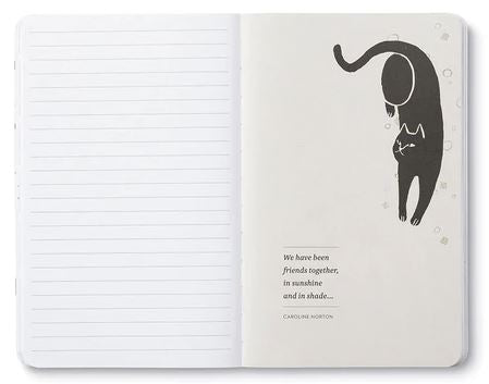 An open COMPENDIUM No Ordinary Cats notebook with lined pages on the left. On the right page, there is an illustration of a black cat playfully upside down with paw prints, and a bold sentiment below: "We have been friends together, in sunshine and in shade." - Caroline Norton.