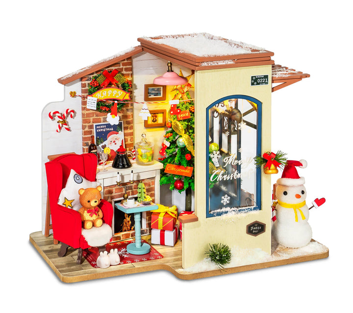 The Christmas Patio DIY Miniature House Kit by Robotime beautifully depicts a charming Christmas-themed room, complete with a Santa chair, teddy bear, presents, and a festively adorned tree. The exterior showcases a snow-dusted roof along with an adorable snowman. A "Merry Christmas" sign on the door perfectly encapsulates the vibrant holiday atmosphere in this 3D wood puzzle creation.