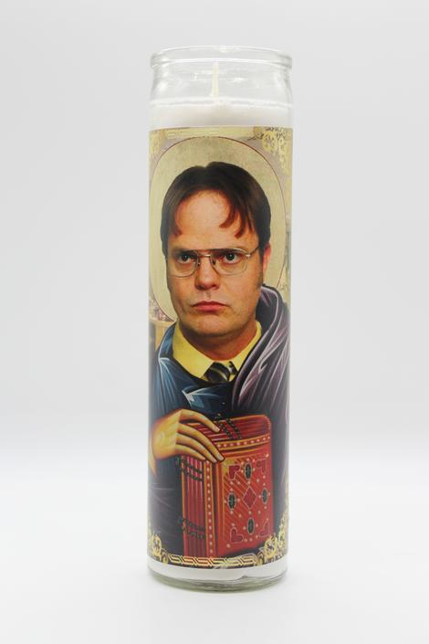 Introducing the Dwight Schrute Candle by BOBBYK BOUTIQUE. This unscented candle features an image reminiscent of a saint's icon, showcasing Dwight from The Office wearing glasses and a stern expression. He is depicted holding a red book embellished with decorative elements, and a halo encircles his head set against a light background. Perfect for any fan!