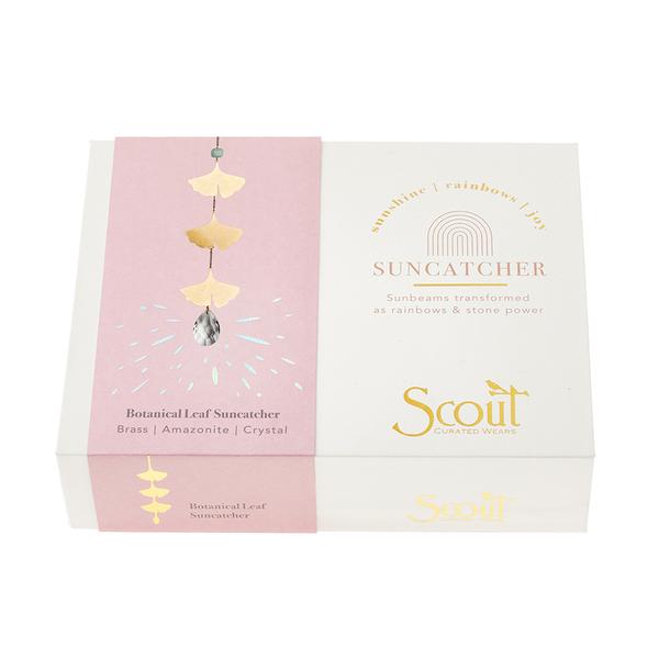 A product box featuring a Leaf Amazonite Suncatcher design. The left side is pink, adorned with an illustration of dangling leaves that capture rainbows from a crystal. The right side is white, showcasing "Suncatcher" in gold text above "Scout Jewelry" at the bottom, suggesting the inclusion of semi-precious gemstones inside.