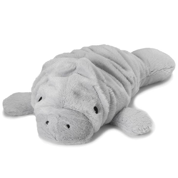 A Manatee Warmies plush animal from the brand Warmies is lying on a white surface. The toy is soft and gray, featuring small black eyes and a texture that mimics the folds and round shape of a real manatee. Infused with French lavender, it has flippers at the front and a flat tail at the back.