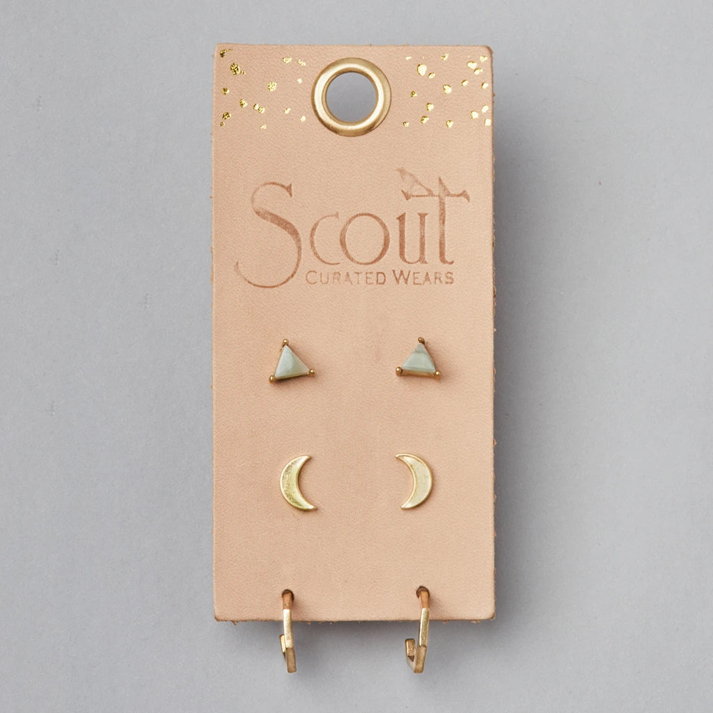 A card labeled "Scout Jewelry" presents the "Ella Stud Trio Labradorite Gold," featuring two pairs of hypoallergenic stud earrings: small 14k gold triangle studs and crescent moon-shaped studs. All are elegantly displayed on a beige card with gold flecks and a convenient hanging hole at the top.