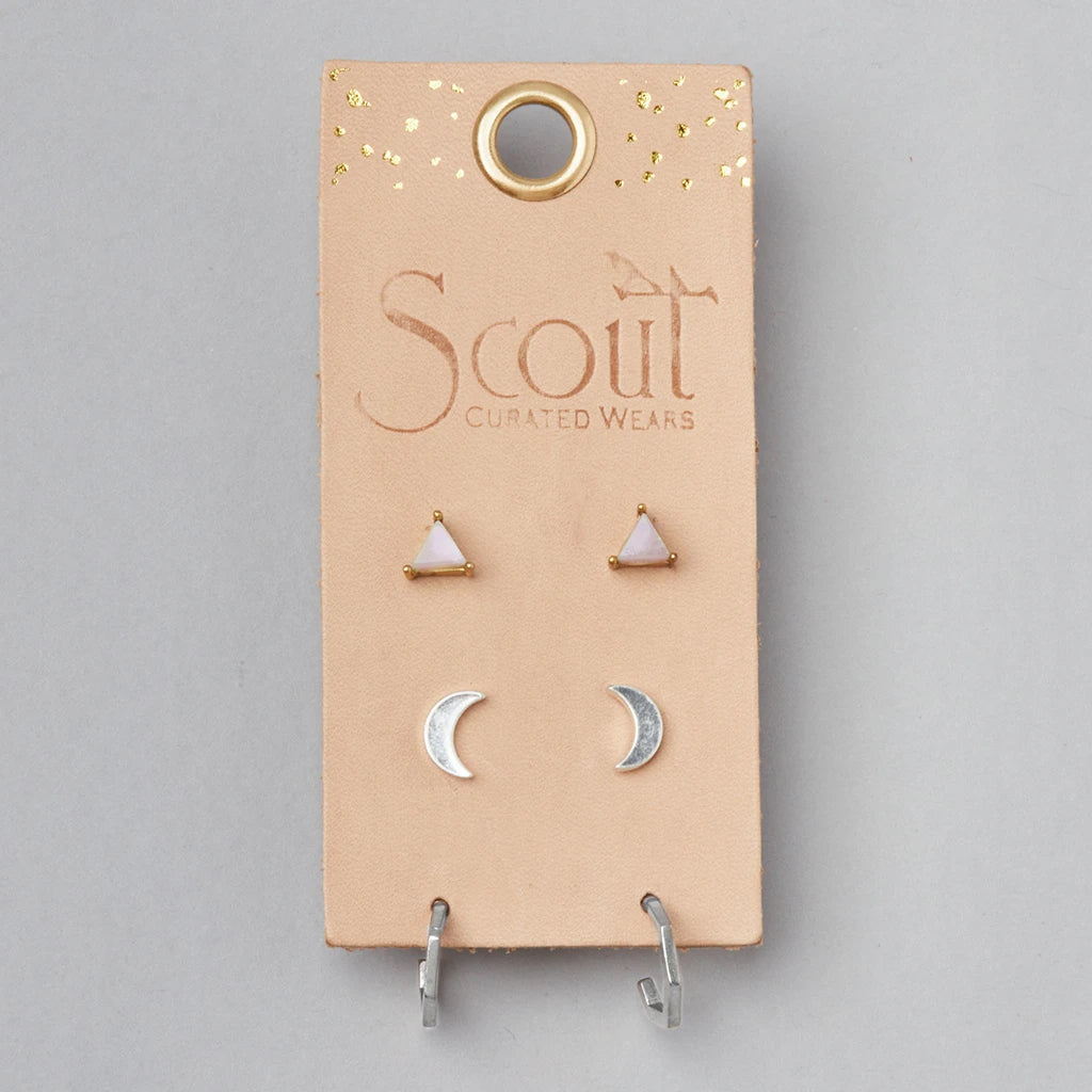 A display card from "Scout Jewelry," labeled with the product name "Ella Stud Trio Rose Quartz Silver," presents two pairs of hypoallergenic earrings: one pair featuring 14k gold-trimmed white triangle stud designs, and the other showcasing silver crescent moon shapes, all against a simple background.